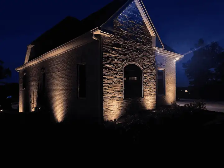 Outdoor lighting illuminating the stone entrance of a home at night.