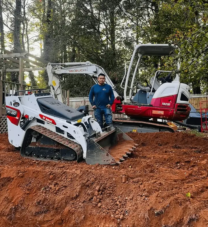 A crew member with landscaping equipment at a job site.